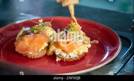 Ein frisch zubereiteter Räucherlachs und Rührei auf Toast, mit Honig und Senf Dressing getränkt Stockfoto