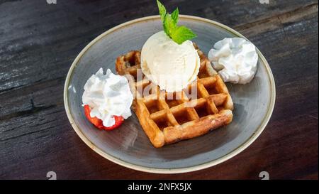 Ein Bild einer frisch zubereiteten Waffel, begleitet von Schlagsahne und Eis Stockfoto