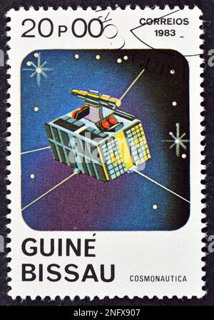 Abgesagte Briefmarke, gedruckt von Guinea-Bissau, auf der Satellit, Kosmonautiktag, um 1983. Stockfoto