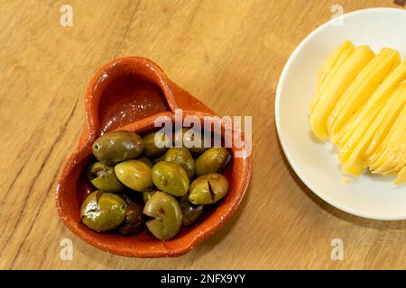 Oliven in einem traditionellen Alentejo-Behälter aus Ton und traditionellem Alentejo-Schafskäse. Stockfoto