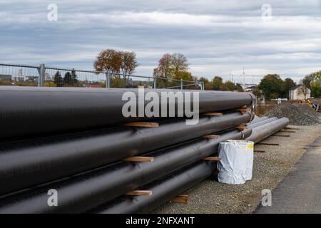 Auf der Baustelle werden große schwarze Metallrohre mit Kunststoffummantelung verlegt. Grauer Himmel mit Wolken. Stockfoto