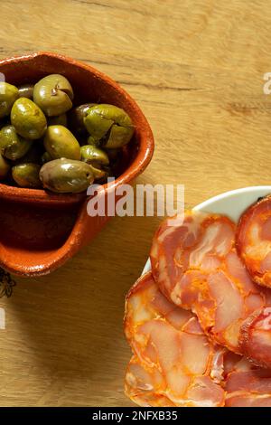 Gericht mit Scheiben Paio und Oliven in einem traditionellen Alentejo-Olivenbaum aus Lehm. Paio ist eine traditionelle Schweinewurst aus der Region Alentejo Stockfoto