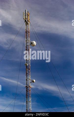 Telekommunikationsturm mit Radio, Mikrowelle und TV-Antennensystem im Wald vor dem blauen Himmel. Antennenturm, Ansicht vom g Stockfoto