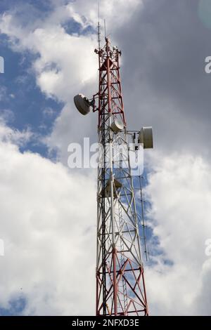 Telekommunikationsturm mit Radio, Mikrowelle und TV-Antennensystem im Wald vor dem blauen Himmel. Antennenturm, Ansicht vom g Stockfoto