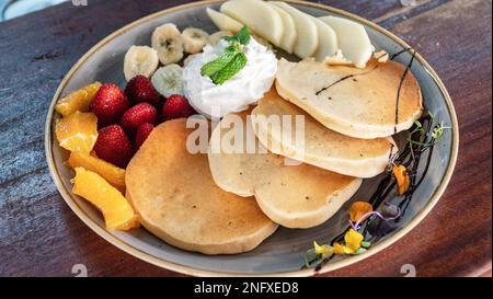 Ein Bild von frisch zubereiteten amerikanischen Pfannkuchen, abgetrennt mit frischem Obst und Sahne aus nächster Nähe Stockfoto