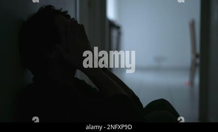 Ein depressiver junger Mann, der an einer psychischen Erkrankung leidet und sein Gesicht mit Bedauern verdeckt. Angstgefühle und Depressionen bei männlichen Personen Stockfoto