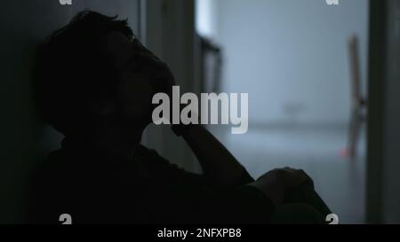 Ein depressiver junger Mann, der an einer psychischen Erkrankung leidet und sein Gesicht mit Bedauern verdeckt. Angstgefühle und Depressionen bei männlichen Personen Stockfoto