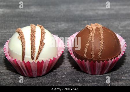 Set aus Schokoladenbomben, gefüllt mit Marshmallows und weißer Schokolade auf altgrauem Hintergrund Stockfoto