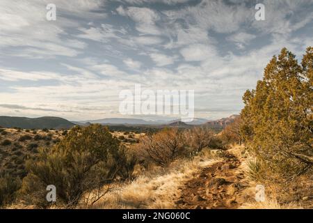 Wanderweg am beliebten Airport Mesa Loop Hike in Sedona, Arizona, USA, im Südwesten während des Tages mit wunderschönen Wolken am Himmel mit Blick nach Westen. Stockfoto