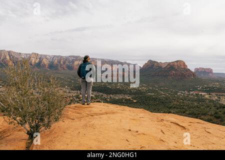 Die junge Frau aus dem Jahr 30s steht und genießt den Sonnenuntergang in Sedona, Arizona, vom Flughafen Mesa Vortex aus gesehen, mit Blick auf die roten Felsenklippen Stockfoto