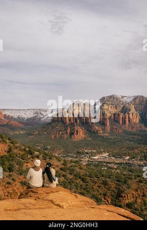 Ein junges heterosexuelles Paar genießt den Sonnenuntergang in Sedona, Arizona, vom Flughafen Mesa Vortex aus gesehen, mit Blick auf die roten Felsenklippen Stockfoto