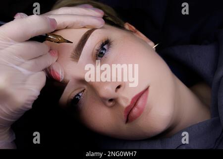 Augenbrauen-permanentes Make-up, Augenbrauentattoo-Verfahren mit Hilfe einer Tattoo-Maschine in der Pulvertechnik Stockfoto