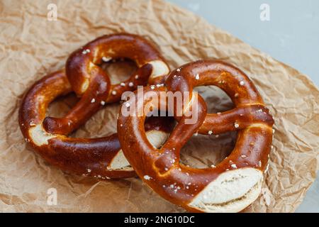 Zwei hausgemachte, frisch gebackene, weiche Brezeln auf braunem Papier. Traditionelle bayrische Brezel für das Oktoberfest. Schließen Stockfoto