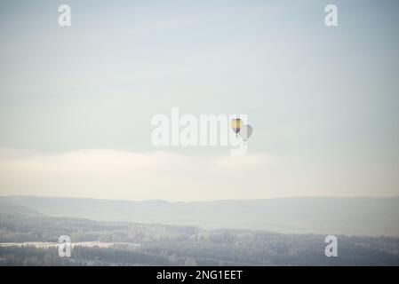 Heißluftballons fliegen über einer Winterlandschaft in Norwegen Stockfoto