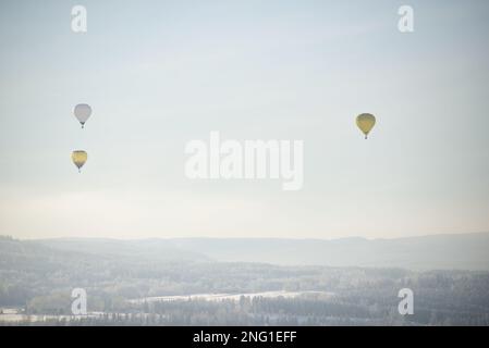 Heißluftballons fliegen über einer Winterlandschaft in Norwegen Stockfoto