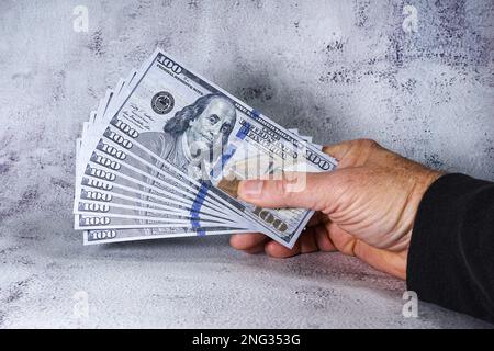 Mans Hhand hält 1000 Dollar in gefälschten oder Requisiten 100 Dollar Scheinen Stockfoto