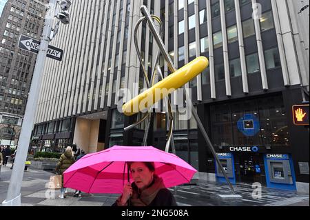 New York, USA. 17. Februar 2023. Eine Frau unter einem rosa Schirm posiert bei der neuen riesigen „Button“-Skulptur im Garment District of New York City, NY, 17. Februar 2023. Die renovierte Skulptur befindet sich in der 39. Street und der 7. Avenue und ist nun 28 Meter hoch. Die gelbe Aluminiumscheibe hat einen Durchmesser von 15 Metern. (Foto: Anthony Behar/Sipa USA) Guthaben: SIPA USA/Alamy Live News Stockfoto