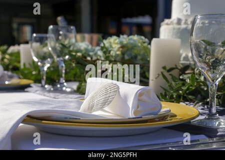 Elegante Tischgestaltung mit grünem Busho-inspiriertem Herzstück, Muscheln und weißem Leinentuch für eine Verlobungsfeier, einen Hochzeitsempfang oder Stockfoto