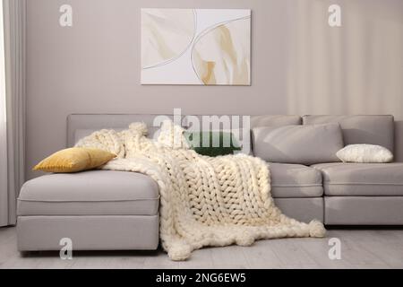 Wohnzimmereinrichtung mit gestrickter Merinowolldecke auf dem Sofa Stockfoto