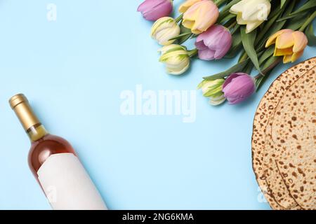 Schmackhafte Matzen, Wein und Tulpen auf hellblauem Hintergrund, flach liegend mit Platz für Text. Pessach-Feier Stockfoto
