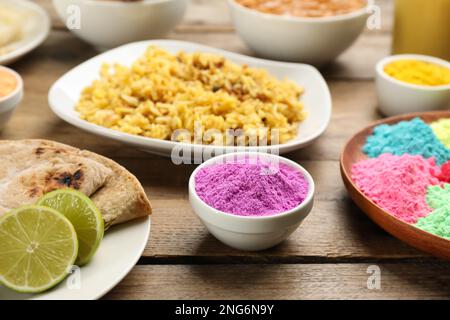 Traditionelle indische Speisen und Farbpulver auf Holztisch. Holi-Festival-Feier Stockfoto