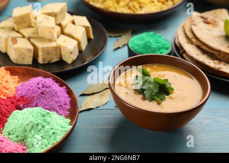 Traditionelle indische Speisen und Farbpulver auf hellblauem Holztisch. Holi-Festival-Feier Stockfoto