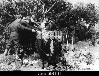 Die Anfangsphase des Holocaust war nicht mit Gaskammern, sondern mit mobilen Hinrichtungstruppen namens Enisatzgruppen. Ihre Aufgabe war es, hinter der Front zu streiten und alle Juden zu erschießen, die sie kriegen konnten. Sie töteten schätzungsweise zwei Millionen Menschen. Dieses Foto zeigt die Männer, die auf ihre Opfer schießen, knien an einem Graben, in den ihre Körper fallen werden. Stockfoto