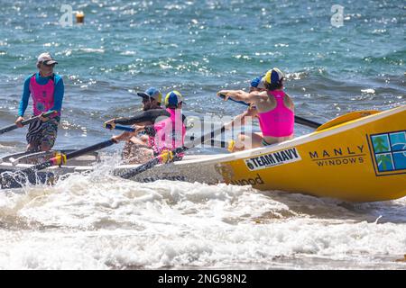 Australische männliche Surfbootcrew rudert ihr traditionelles Surfboot auf dem Collaroy Beach Surf Carnival, 2023, Sydney, Australien Stockfoto