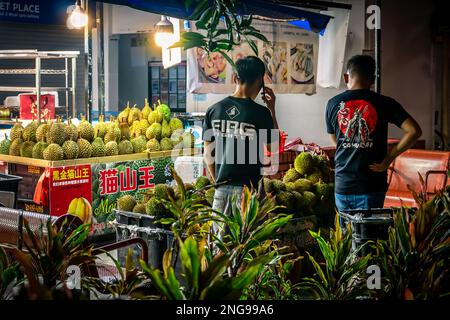 Kunden, die Durianfrüchte in einem Duriangeschäft in Wohnsiedlung in Singapur kaufen. Stockfoto