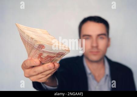 Geschäftsmann, der Geld spendet, russische Rubel-Banknoten, Bestechungs- und Korruptionskonzept. Ein großer Geldhaufen mit einer Million Rubel in der Hand eines Erfolgs Stockfoto