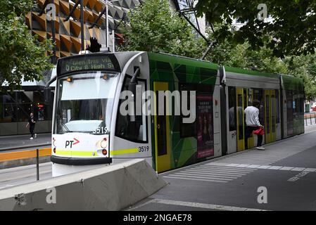 Yarra Trams D-Klasse oder Combino, Straßenbahn an einer Haltestelle auf der Swanston Street, während ein Passagier versucht, durch eine teilweise offene Tür auszusteigen Stockfoto