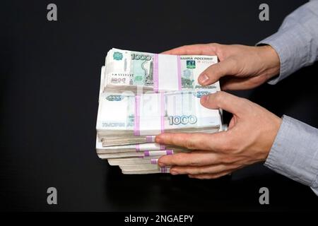 Ein Geschäftsmann, der viel Geld hat. Geld, Finanzen, Geschäftskonzept. Russische Rubel in Bündeln auf dem Tisch. Millionen Rubel Stockfoto