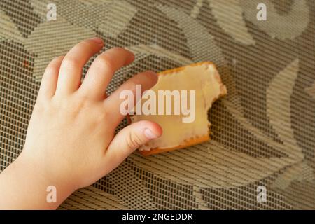 Kinderhände und Kekse mit Butter auf dem Tisch Stockfoto