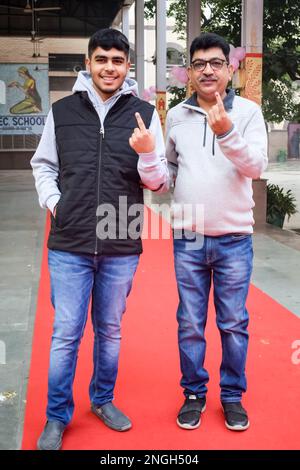 Neu-Delhi, Indien - Dezember 04 2022 - Unbekannte zeigen ihre mit Tinte markierten Finger, nachdem sie vor dem Wahlstand von Ost-Delhi Stimmen abgegeben haben Stockfoto