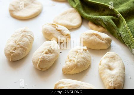 Rohe Pasteten mit Kartoffeln auf einem weißen Tisch in der Küche, hausgemachte Pasteten Stockfoto