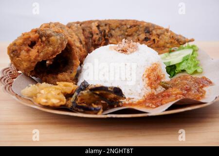Gebratener Catfish mit scharfer Sauce, Reis und Gemüse auf einem Teller (Pecel Lele) Stockfoto