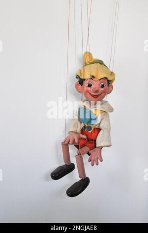 Eine klassische Marionettenpuppe auf einer Pinocchio-Kette vor weißem Hintergrund Stockfoto