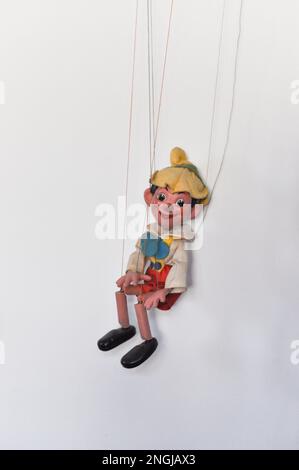 Eine klassische Marionettenpuppe auf einer Pinocchio-Kette vor weißem Hintergrund Stockfoto