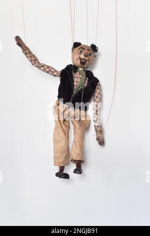 Eine handgefertigte Marionettenpuppe auf einer Kette einer Clown-ähnlichen Figur vor weißem Hintergrund Stockfoto