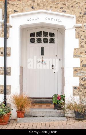 Eine malerische Tür im Fischerdorf Beer in Devon, England. Die weiß bemalte Veranda markiert den Eingang zum Beach Cottage. Stockfoto
