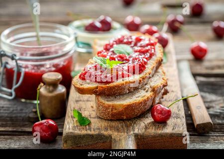 Sandwich mit Marmelade aus Kirschen im Sommergarten. Frisches Obst aus dem Garten. Stockfoto