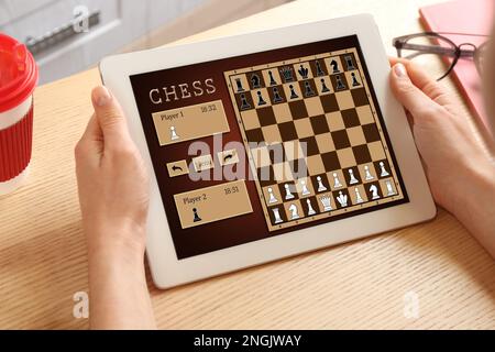 Frau, die online Schach auf einem Tablet spielt, drinnen, Nahaufnahme Stockfoto