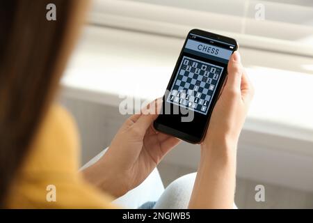 Frau, die online Schach auf Smartphone spielt, drinnen, Nahaufnahme Stockfoto
