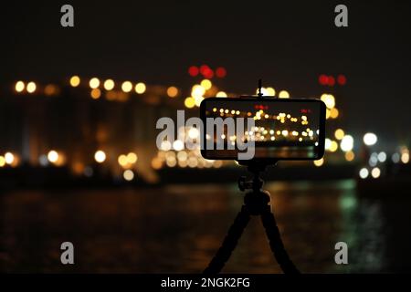 Fotografieren Sie die wunderschöne Stadtlandschaft bei Nacht mit dem auf dem Stativ montierten Smartphone Stockfoto