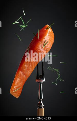 Gesmokter Lachs mit Rosmarin auf schwarzem Hintergrund. Stockfoto