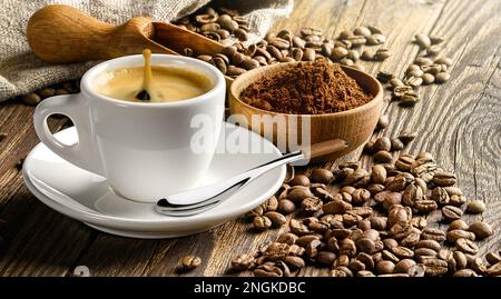 Kaffeetasse und Bohnen auf altem Holztisch. Stockfoto