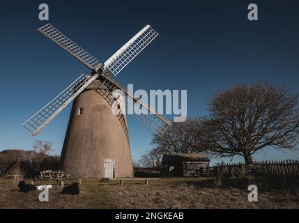Die Bembridge Windmühle steht auf einer riesigen Wiese mit einem wolkenlosen Himmel, der sich dahinter erstreckt Stockfoto