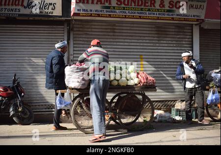 Ein Frischgemüsehändler, der Produkte wie Möhren und Kohl von einem Karren in den Straßen von Old Delhi verkauft Stockfoto