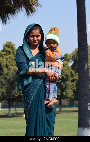 Eine junge indische Mutter in einem traditionellen Sari, die ihr kleines, etwa 1 Jahr altes Baby hält Stockfoto