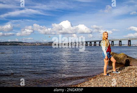 An einem wunderschönen Oktobertag in Wormit Beach, Fife, wirft Rhianna Martin Kiesel über ihren Kopf in den Fluss Tay, Schottland Stockfoto